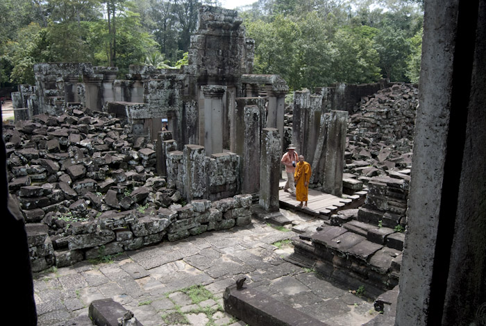 Bayon courtyard with rubble, monk, and tourist