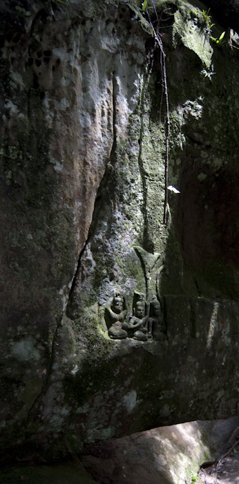 small seated figures in rock face