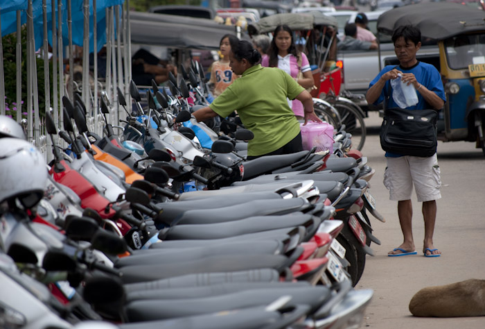 motorcycle parking row with woman reaching for helmet